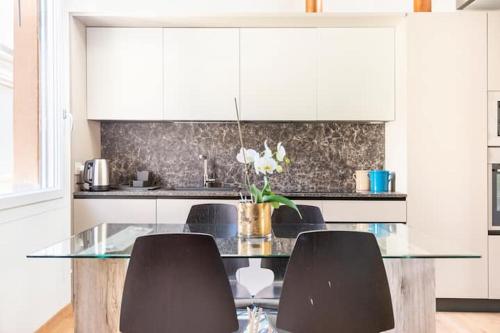 a kitchen with a glass table and some chairs at Domus: modern Loft in the center of Parma in Parma