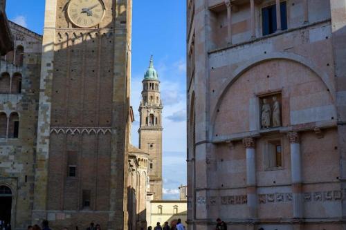 a clock tower and a building with a clock at Domus: modern Loft in the center of Parma in Parma