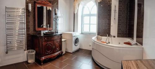 a bathroom with a tub and a sink and a washing machine at Guest house Florinda in Jūrmala