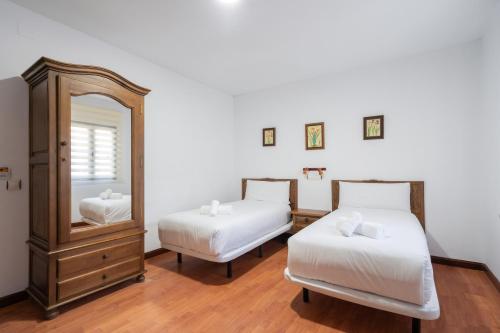a bedroom with two beds and a mirror and a dresser at Hotel La Quinta de Santillán in Chinchón