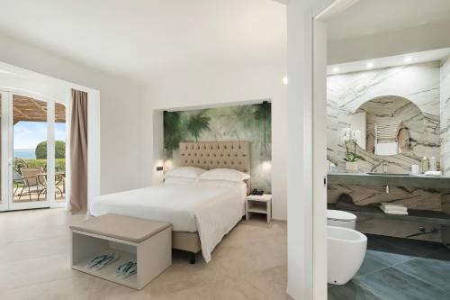 a white bedroom with a bed and a bathroom at Hotel Villa Domizia in Porto Santo Stefano