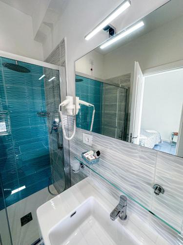 a bathroom with a sink and a shower and a mirror at Hotel Poseidon in Diamante