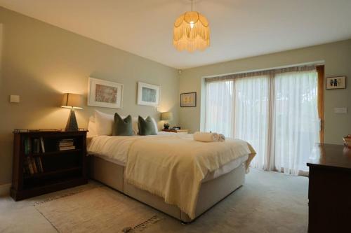 a bedroom with a large bed and a chandelier at Musthay Mews Tockington cottage in Bristol