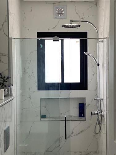 a bathroom with a glass shower with a window at Marsa - Sidi Bousaid Lovely Authentic Apartment in La Marsa