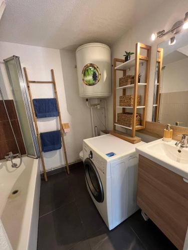 une salle de bain avec une machine à laver et un lavabo dans l'établissement Maison proche de la plage, à Vic-la-Gardiole