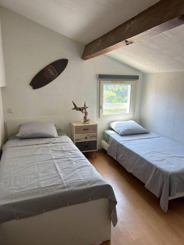 - une chambre avec 2 lits et une planche de surf sur le mur dans l'établissement Maison proche de la plage, à Vic-la-Gardiole