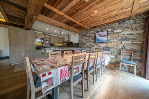 une cuisine avec une table et des chaises et un mur en pierre dans l'établissement Appartement Le Rosset, à Tignes