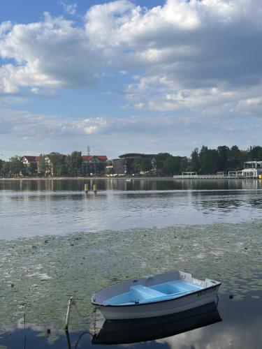 a small boat sitting in the water on a lake at Apartament nad Jeziorem Drwęckim w Ostródzie z klimatyzacją in Ostróda