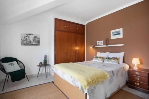 a bedroom with a bed and a chair at Porto Dinheiro Beach I in Lourinhã