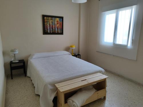 a white bedroom with a bed and a window at La Longuera - Playa Cruz del Mar in Chipiona