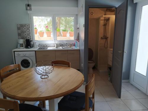 - une cuisine avec une table en bois, des chaises et un évier dans l'établissement Studio de la pinède, à Nissan-lez-Enserune