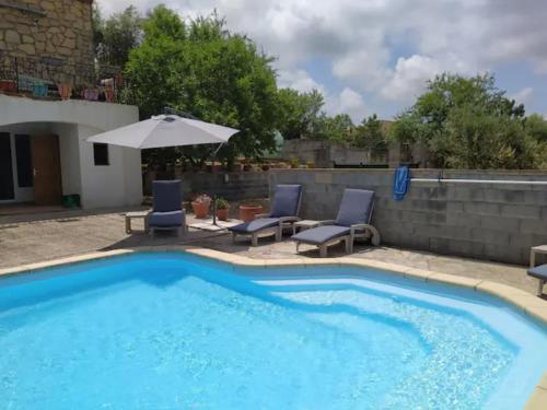 une piscine avec deux chaises et un parasol dans l'établissement Studio de la pinède, à Nissan-lez-Enserune