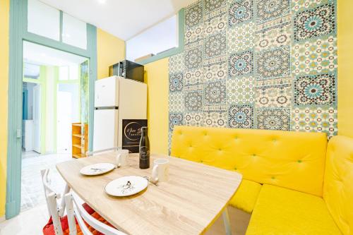 une salle à manger avec une table et un canapé jaune dans l'établissement 2P hyper-centre Nice, à Nice