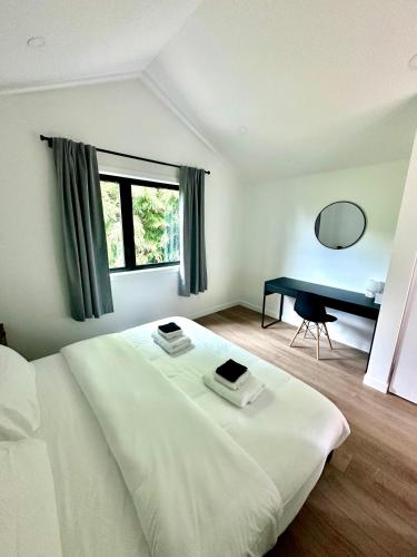 a bedroom with a white bed and a desk at cottage NOMAD in Ucluelet
