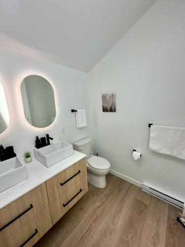 a white bathroom with two sinks and a toilet at cottage NOMAD in Ucluelet