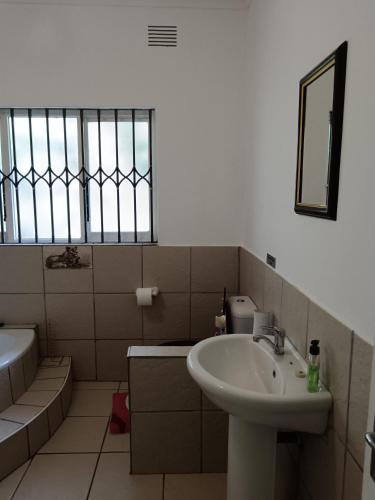 a bathroom with a sink and a toilet and a window at Peaceville in Port Shepstone