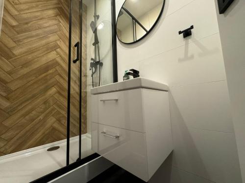 La salle de bains blanche est pourvue d'une douche et d'un miroir. dans l'établissement Central Newest Studio Bastova, à Košice