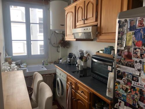 La cuisine est équipée d'un réfrigérateur et d'un évier. dans l'établissement Appartement chaleureux proche Paris, à Montrouge