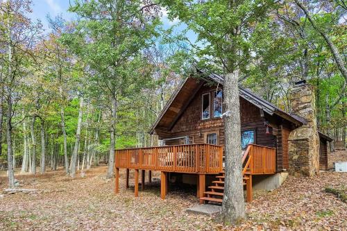 a log cabin with a deck in the woods at Log Cabin w Loft, Hot Tub, Deck, Fire Pit, & WiFi in Great Cacapon