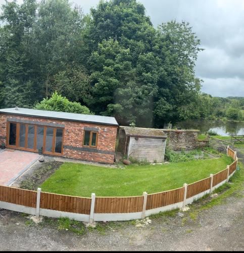 a small brick house with a fence around it at Goldie's Retreat in Blackrod