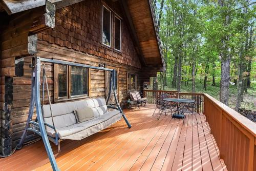 a porch of a log cabin with a couch and a table at Log Cabin w Loft, Hot Tub, Deck, Fire Pit, & WiFi in Great Cacapon