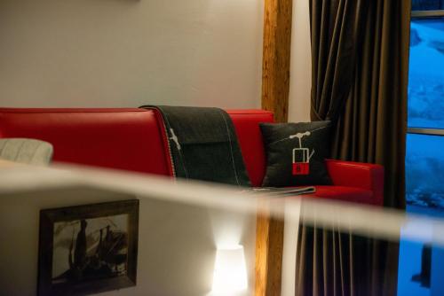 a living room with a red couch and a window at Mountainlodge Luxalpine in San Vigilio Di Marebbe