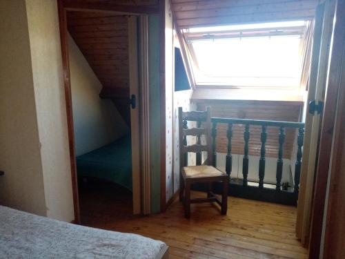 Cette chambre comprend un lit, une fenêtre et une chaise. dans l'établissement Le Randonneur, à Chastreix