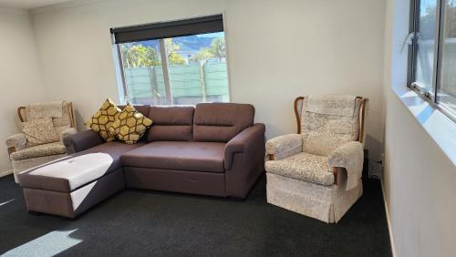 a living room with a couch and two chairs at OakTree Entire Holiday Home, Sleeps 8 to12 in Rotorua