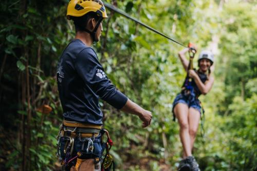 a man and woman on a zip line in the jungle at El Remanso Rainforest Lodge in Puerto Jiménez