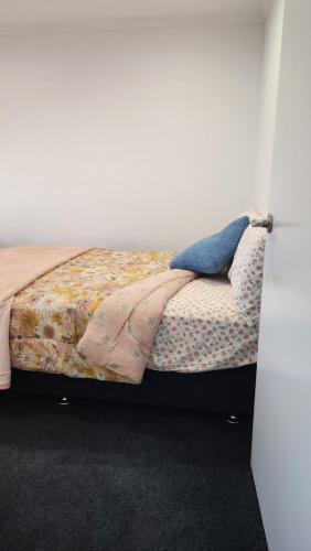 a bed with a blanket and pillows on it at OakTree Entire Holiday Home, Sleeps 8 to12 in Rotorua