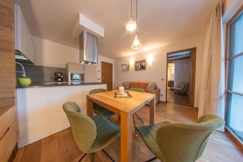 a kitchen and living room with a wooden table and chairs at Mountainlodge Luxalpine in San Vigilio Di Marebbe