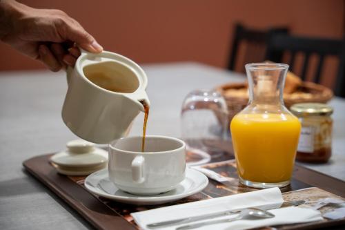 Eine Person gießt Kaffee in eine Tasse auf einem Tablett. in der Unterkunft Domaine la coquillade in Autignac