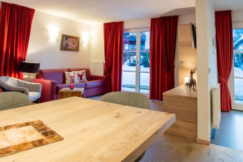 a living room with red curtains and a table at Mountainlodge Luxalpine in San Vigilio Di Marebbe