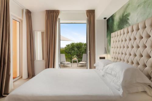 a bedroom with a white bed and a large window at Hotel Villa Domizia in Porto Santo Stefano