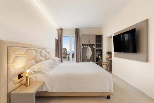 a white bedroom with a large bed and a tv at Hotel Villa Domizia in Porto Santo Stefano