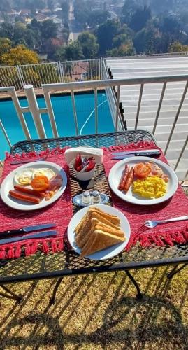 a table with plates of breakfast food on a balcony at Palm View Guest House in Pretoria
