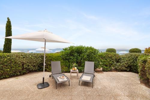two chairs and an umbrella and a table at Hotel Villa Domizia in Porto Santo Stefano