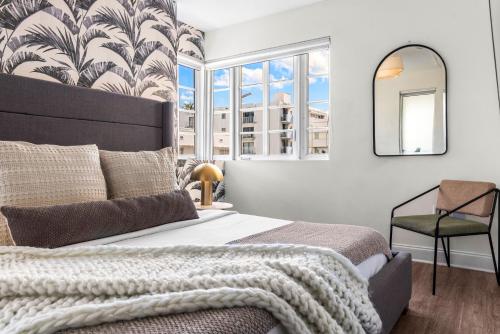 a bedroom with a bed and a mirror and a chair at Luxuri Suites in Miami Beach