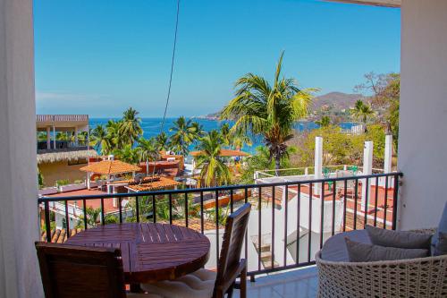 a balcony with a table and chairs and the ocean at Hotel Villas Ema in Zihuatanejo