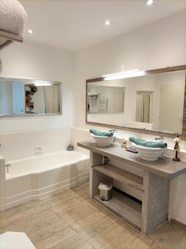 une salle de bain avec deux lavabos, une baignoire et un miroir dans l'établissement chambres d'hôtes la maison de mon père, à Saint Alban Auriolles
