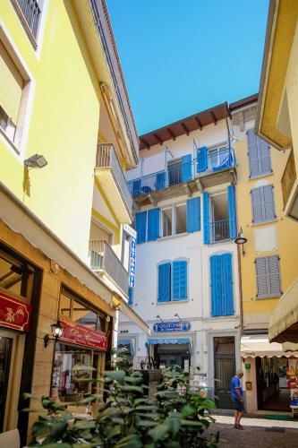 a building with blue windows and a person walking in a street at la Strecia in Stresa