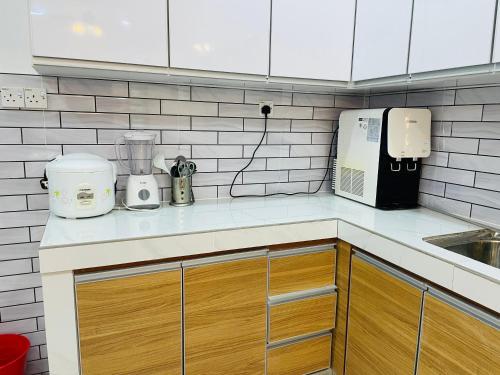 a kitchen with white cabinets and a counter top at Nazirin Homestay No 27 Tmn Desa Manjung Lumut in Lumut