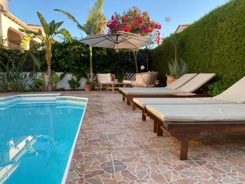 a swimming pool with chaise lounges and an umbrella at Marinea Beach Villas in Paphos