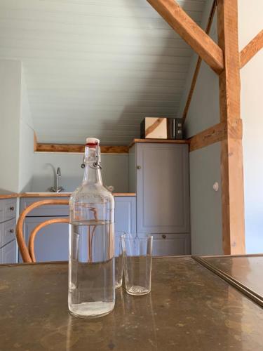 - une bouteille d'eau assise sur une table avec deux verres dans l'établissement Appartement pitoresque dans ancienne ferme, à Kauffenheim