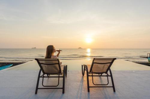 a woman taking a picture of the ocean at sunset at 26Villa Huahin in Khao Tao
