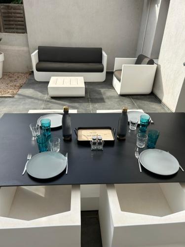 une table à manger noire avec des assiettes et des verres dessus dans l'établissement Jardin secret en plein cœur du Cabot, à Marseille