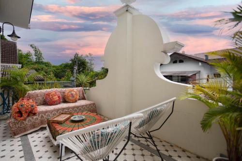 a patio with a couch and a table on a balcony at Pran At Kumuang Boutique House in Chiang Mai
