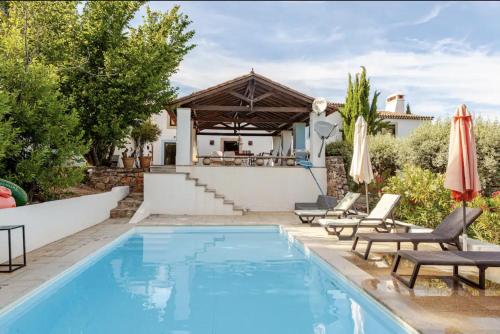 a pool with chairs and umbrellas next to a house at Casa do Chapim-azul in Marvão