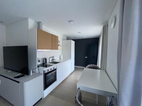 a small kitchen with white cabinets and a table and a tableablish at Pervalkos Jūra apartamentai in Pervalka