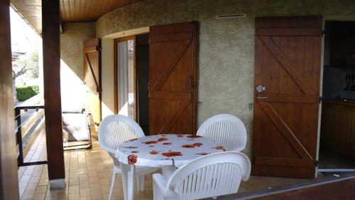 - une table et des chaises assises sur une terrasse couverte avec une porte dans l'établissement Maisonnette, à Cazaubon